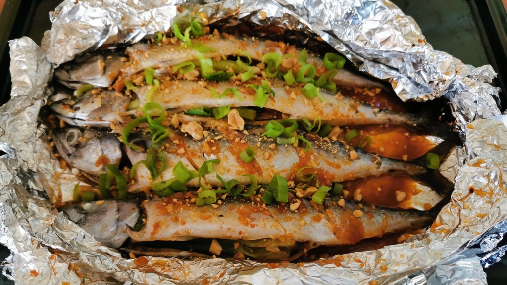 Ein geöffnetes Alufolienpaket bringt die Makrele - vietnamesischer Art nach dem Rezept von schonzeitvertreib.de zum Vorschein, garniert mit Lauchzwiebeln und Erdnüssen