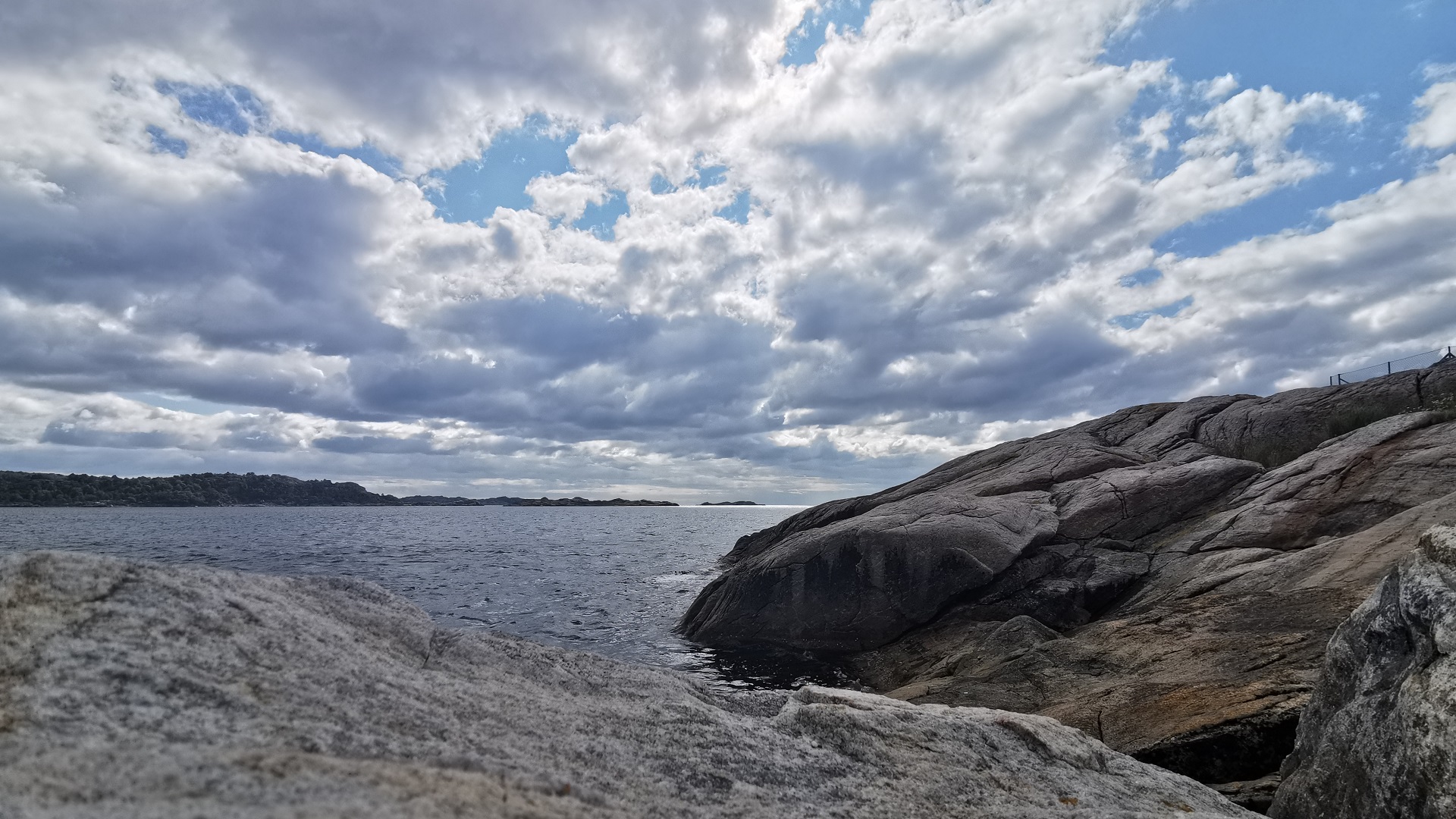 Blick über das Meer in Båly Brygge bei leicht bewölktem Himmel, die Felsen im Vordergrund sind ein guter Stellplatz zum Angeln
