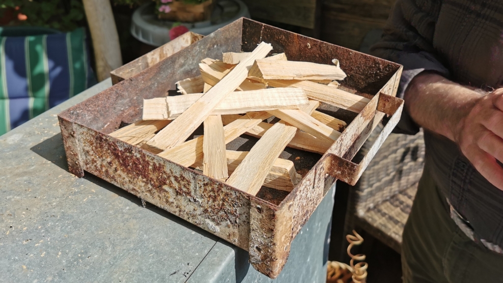 Kleine trockene Holzscheite aus Buchenholz sind in der Schublade der Räuchertonne ausgelegt