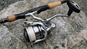 Montierte Shimano Stradic Stationärrolle an einer Spinnrute, ruht auf einem Felsen, bereit für den Fang am Gewässer.