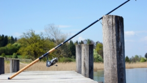 Angelrute auf Steg abgelegt, bereit für das Angeln am malerischen Gewässer.