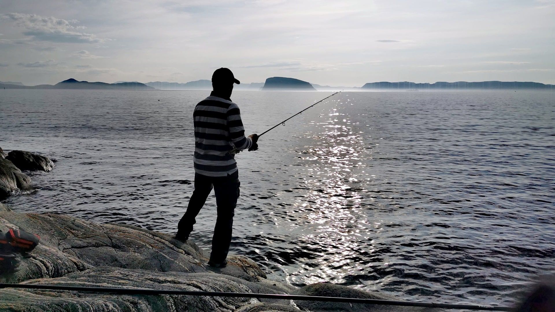 Angler mit Spinnrute angelt auf den Felsen südlich der Wohnmobilstellplätze am Hafen von Hammerfest