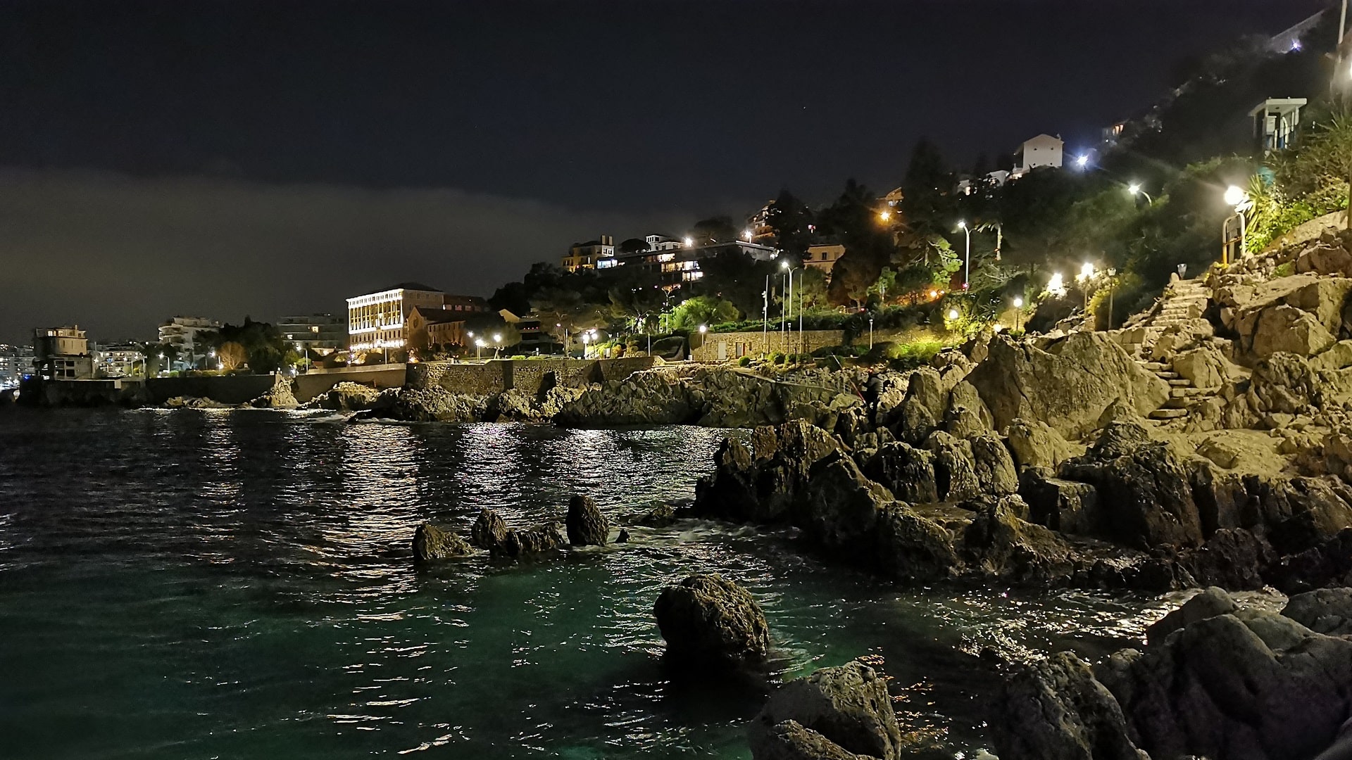 Nächtliche Szene an der felsigen Küste von Nizza mit Straßenbeleuchtung – Angeln auf Kalamar
