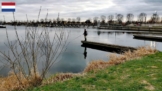 Blick auf den Einlauf am Becken oberhalb der Schleuse in Maasbracht bei Roermond - ein Angler steht auf einer Mauer, an der das Wasser des Schleusenbeckens ins Nebenbecken geleitet wird