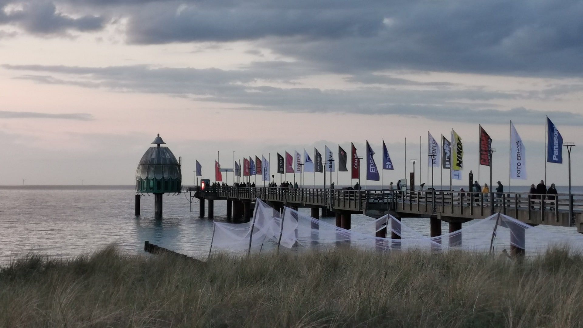 Seebrücke Zingst im sanften Licht des Sonnenaufgangs mit wehenden Fahnen – ein beliebter Ausgangspunkt für das Angeln auf Hornhecht rund um Zingst