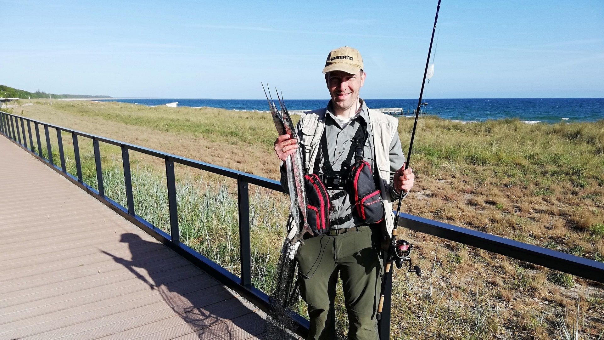 Zufriedener Angler präsentiert zwei prächtige Hornhechte – erfolgreicher Fang beim morgendlichen Angeln an der Seebrücke von Zingst