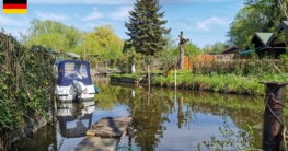 Typische Kulisse beim Angeln in Klein-Venedig inmitten der Tiefwerder Wiesen - Ein Boot liegt an einem kleinen Steg mitten in einer Kleingartenanlage, dichter Uferbewuchs, blauer Himmel und ruhiges Wasser prägen die Atmosphäre