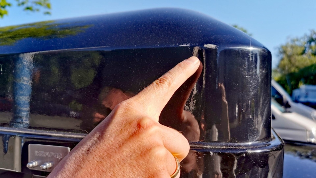 Finger zeigt auf eine Schramme an der Hartschale – Spuren der ersten eigenständigen Dachzelt-Montage für kommende Angelabenteuer.