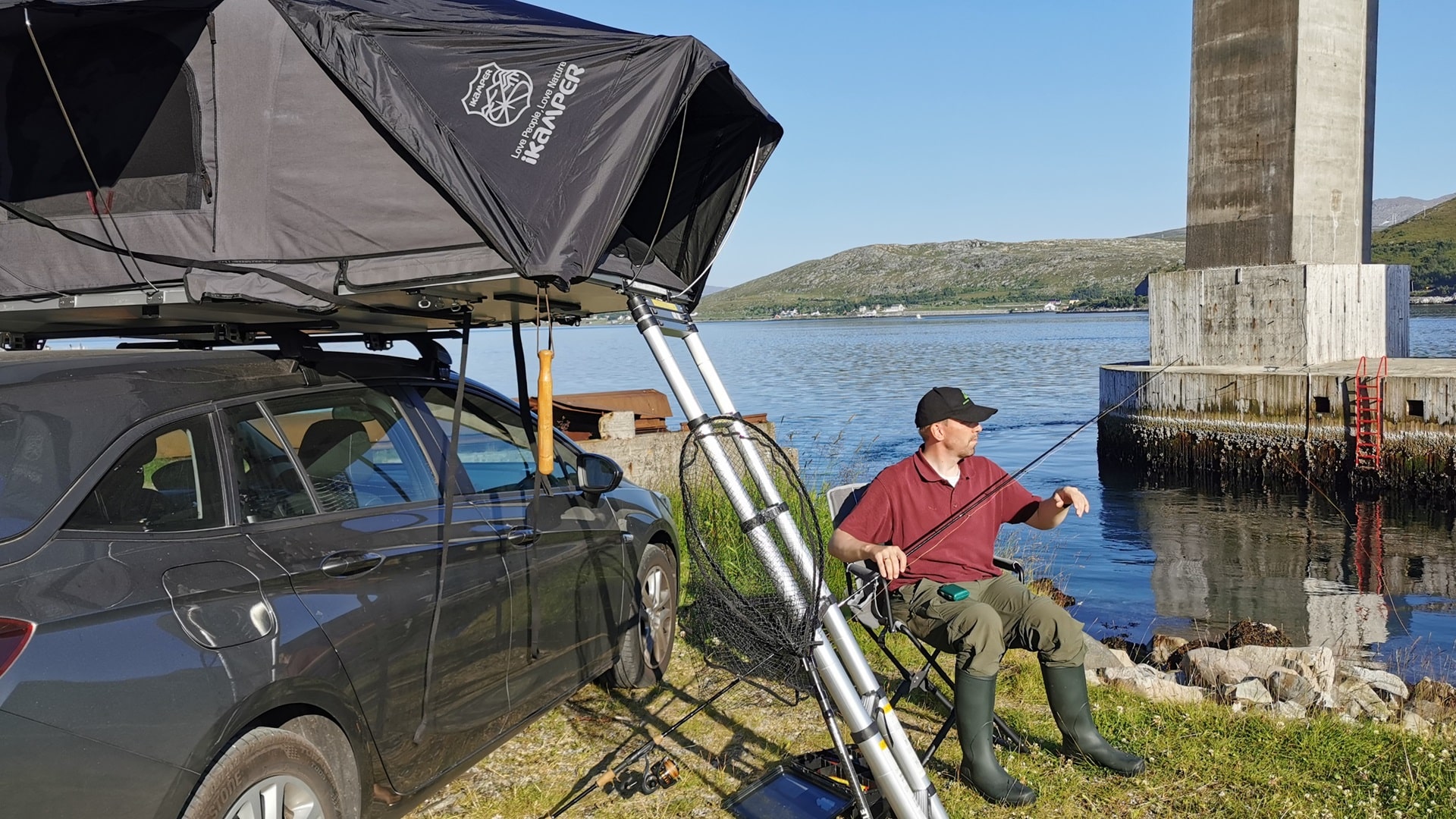 Angler im Campingstuhl beim Aufbau der Ausrüstung zum Angeln unter der Kvalsundbrua, das Dachzelt direkt neben ihm