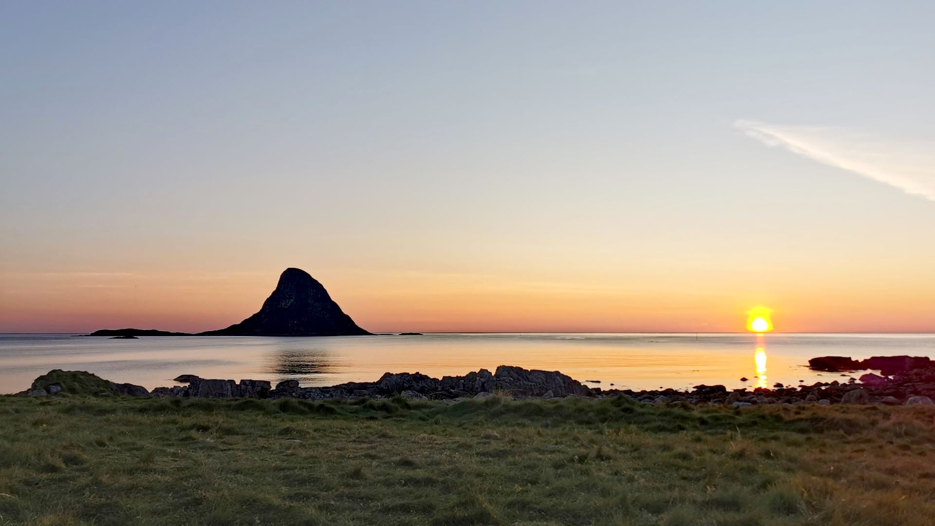 Sonnenuntergang am Bleik Strand taucht den Himmel in leuchtendes Rot, der Felsen in Haiflossenform ragt markant aus dem Meer