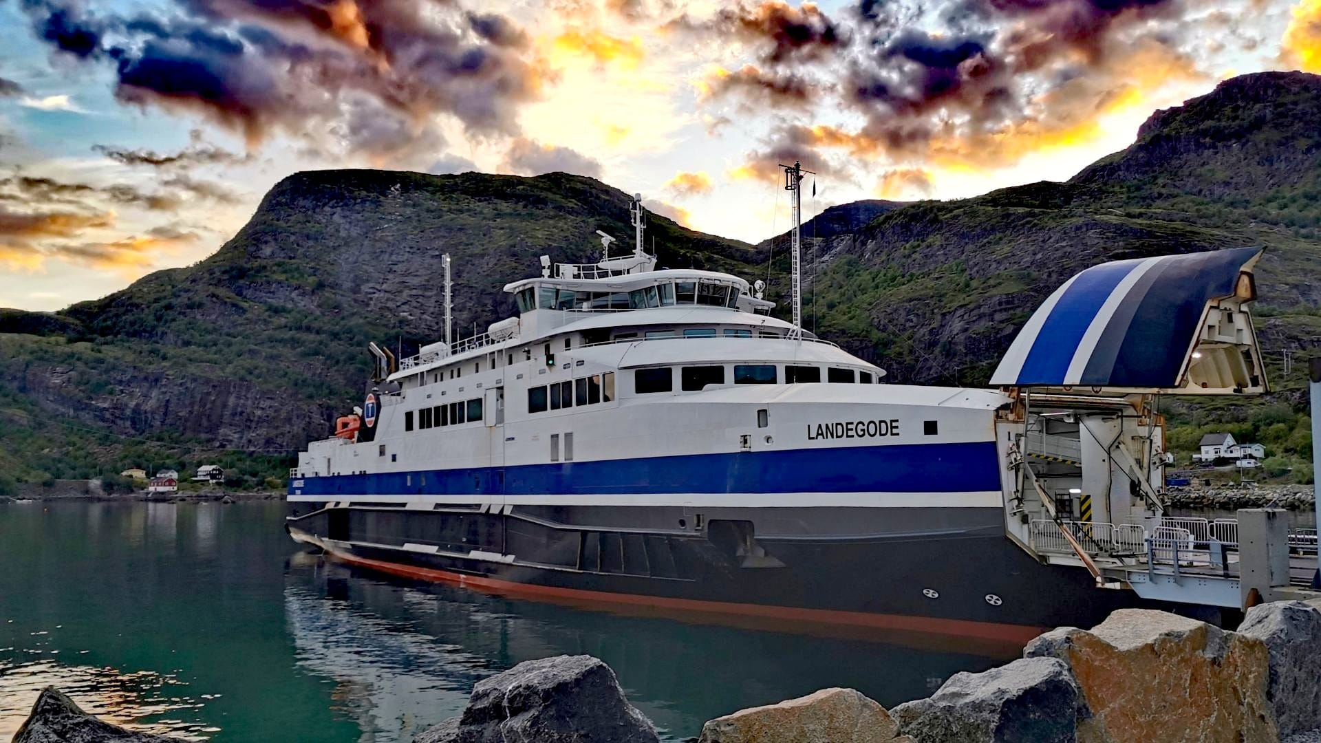 Fähre legt in Moskenes ab Richtung Bodø, während sich am Himmel über den Bergen der Lofoten dramatische Licht- und Wolkenspiele zeigen