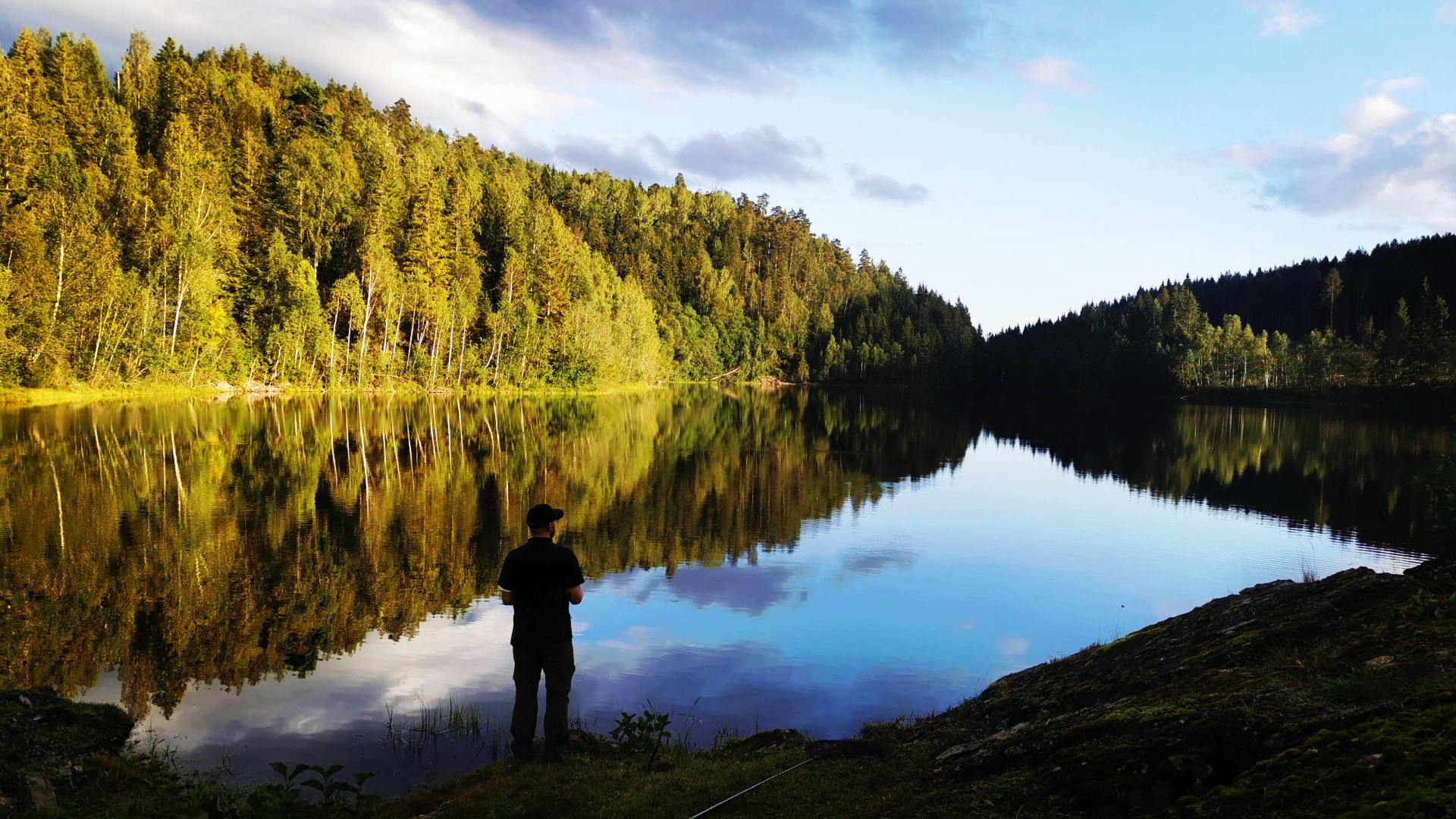Spiegelglatter Stulvann bei Skien mit Angler am Nordufer, tiefstehender Sonne und frühherbstlich gelb-grünen Laubbäumen, die sich im Wasser spiegeln