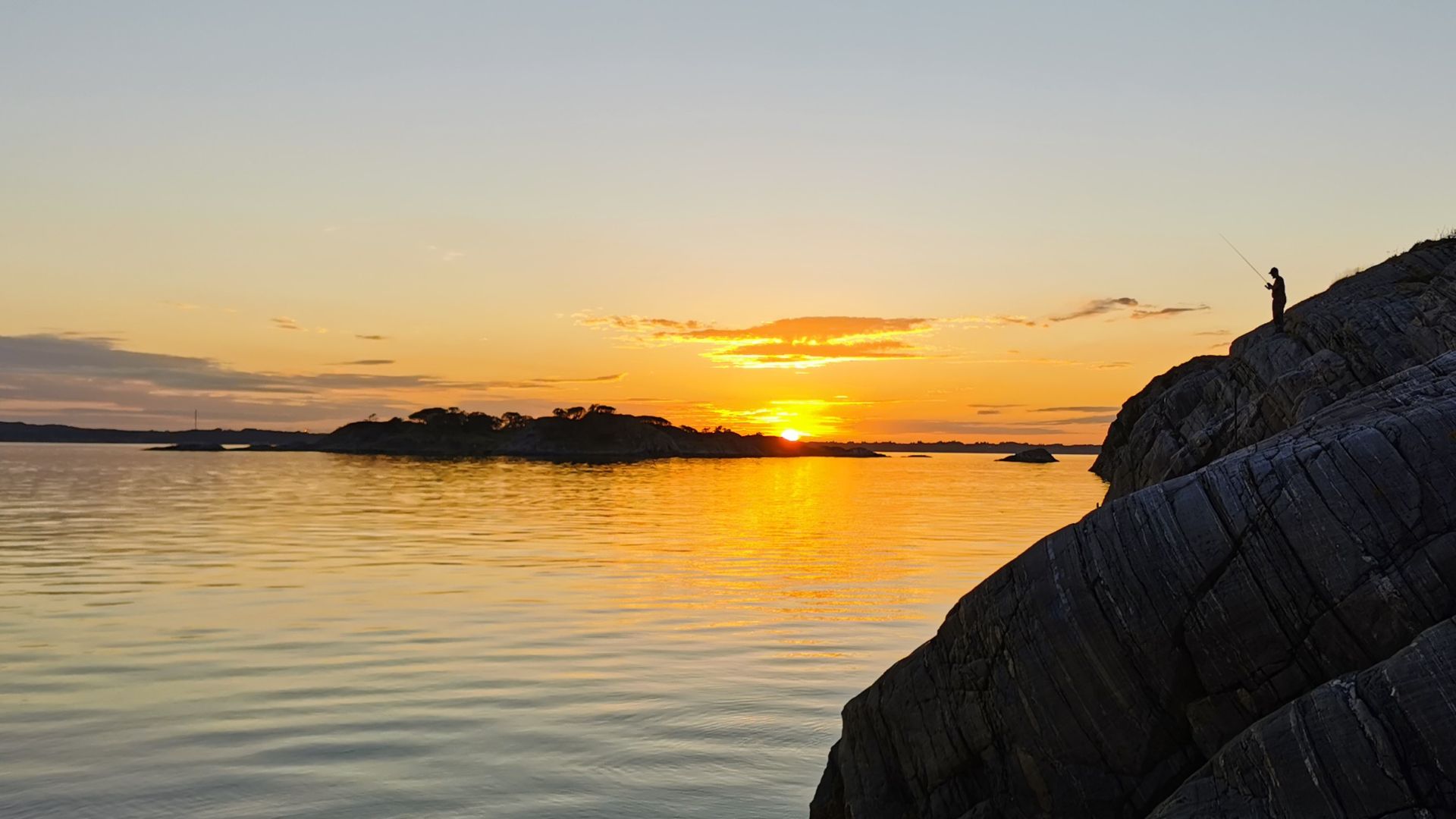 Sonnenuntergang über dem Meer auf Askøy mit Angler-Silhouette – stimmungsvolles Finale einer Angeln mit Dachzelt-Tour bei Bergen
