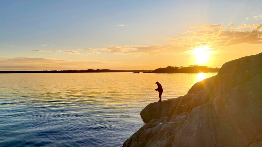 Autor steht auf einem Felsen und angelt mit der Savage Gear Parabellum CCS 10'1 Test-Rute, nur seine schwarze Silhouette ist gegen den farbigen Sonnenuntergang sichtbar.