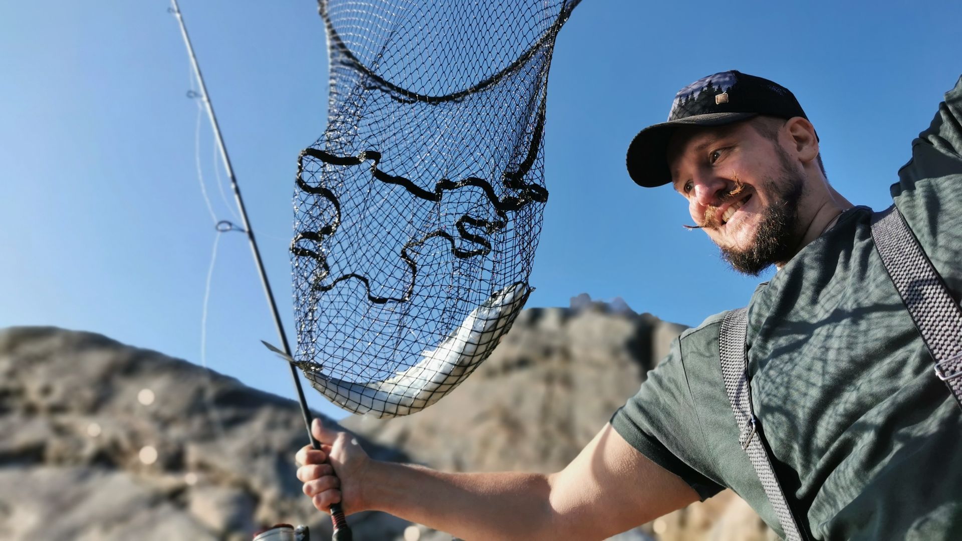 Glücklicher Angler mit Kescher und frisch gefangener Makrele – ein Fangmoment während des Dachzelturlaubs bei Bergen