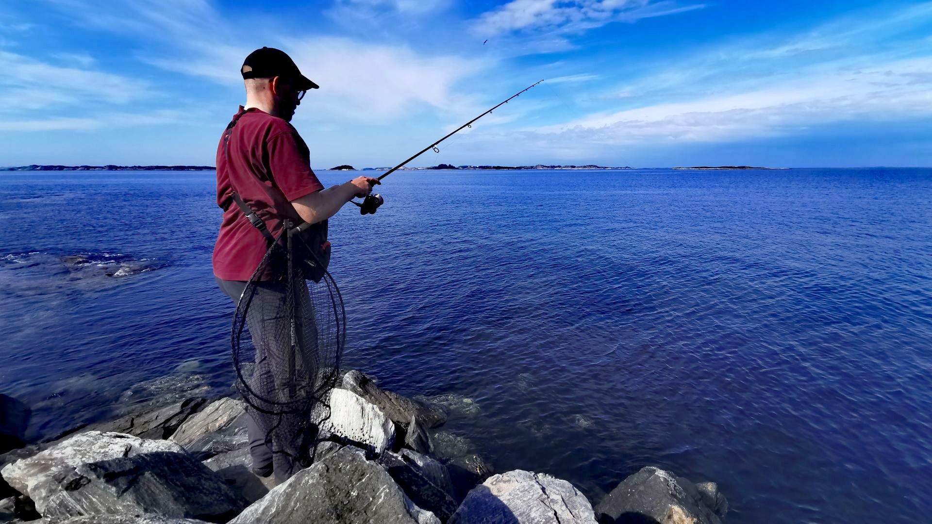 Angler am Nordende von Sotra mit Blick auf spiegelglattes Meer – ein Highlight der Angeln mit Dachzelt-Tour bei Bergen