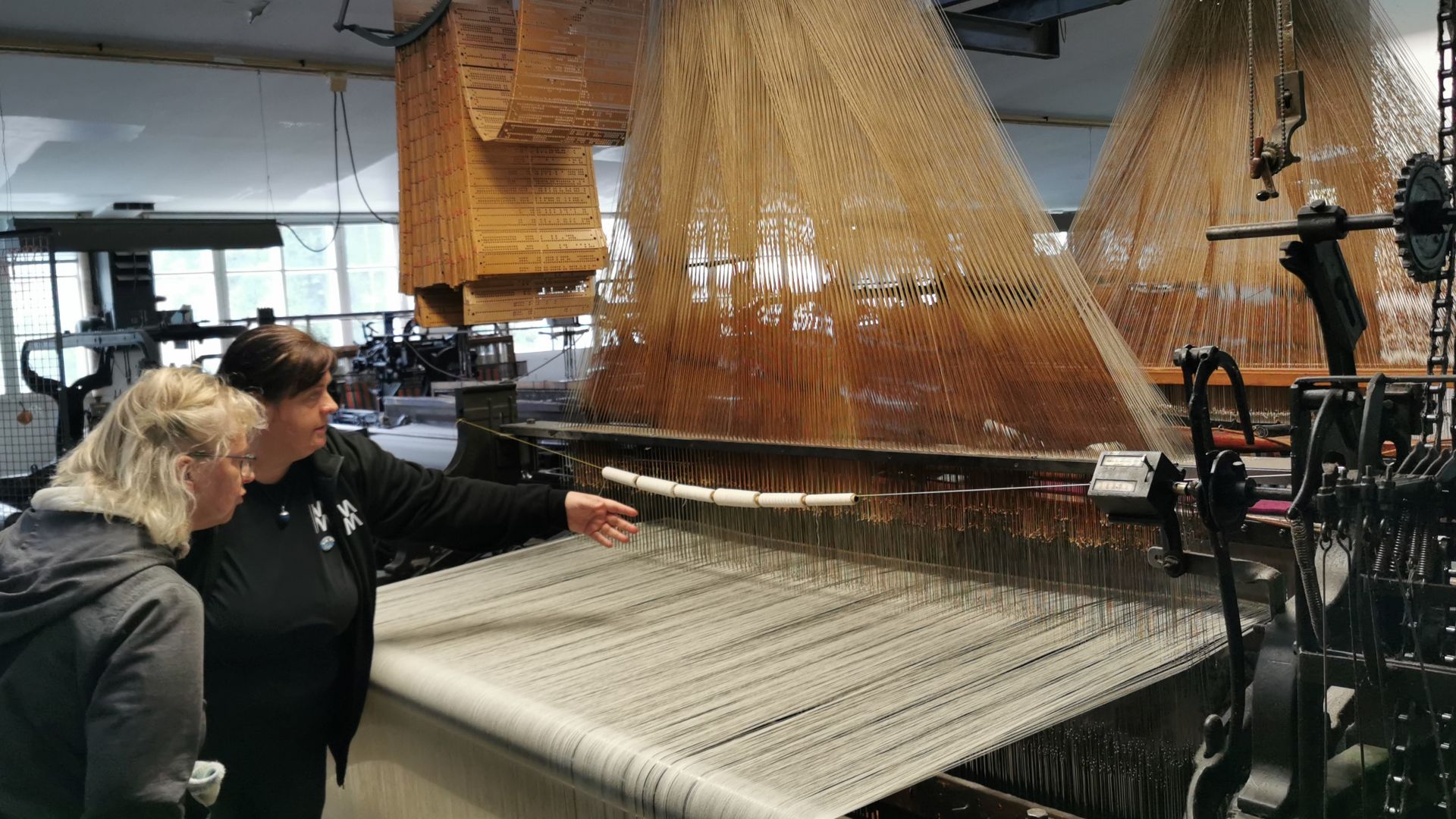 Historischer Webstuhl in der Sjolingstad Uldvarefabrik bei Mandal, bei einer deutschen Führung wird einem Besucher die Arbeitsweise erklärt