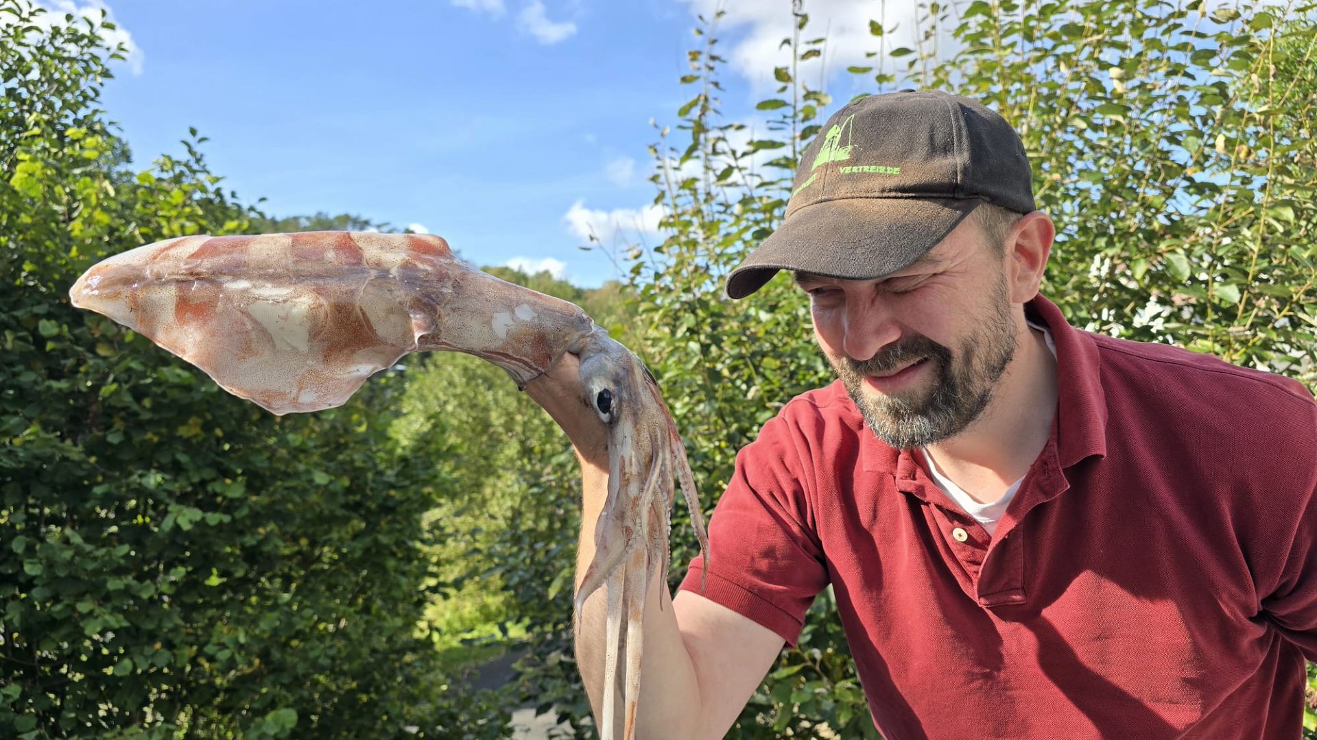 Autor hält einen frisch gefangenen Tintenfisch hoch, der über seinen Arm gestülpt ist – ungewöhnlicher Beifang beim Angeln bei Lyngdal